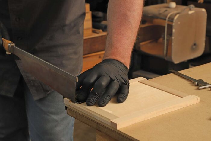 The author uses a saw to cut a notch in the bottom of the door.