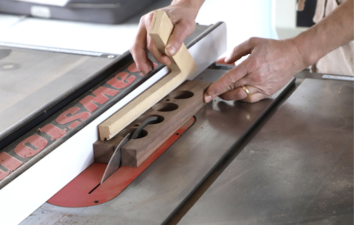 Tom rips a board in half with several holes drilled in it.